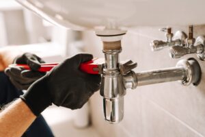 Plumber,in,black,gloves,fixes,a,sink,pipe,with,a