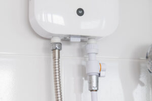 Instant,tankless,electric,water,heater,installed,on,white,tile,wall